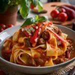 A bowl of Italian Drunken Noodles garnished with fresh basil and cherry tomatoes, served in a rustic Italian setting.
